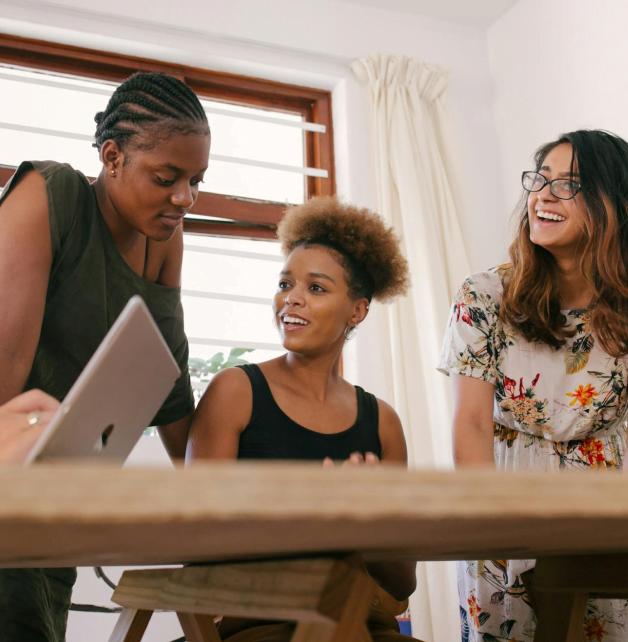 Trois jeunes femmes autour d'une table en train de discuter et d'échanger.